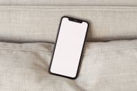 Kaboompics - Blank Phone Screen Standing Against a Linen Sofa Cushion