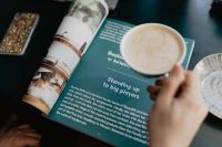 Kaboompics - Hand Holding Coffee Cup Over an Open Magazine