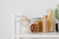 Kaboompics - Glass Pantry Jars with Cookies, Pasta and Chickpeas on a White Shelf with Copy Space