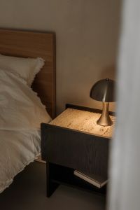 Kaboompics - Black Nightstand with Warm Table Lamp beside White Bed and Neutral Wall