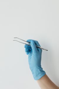 Kaboompics - Curved Dental Tweezers Held in Blue Gloved Hand