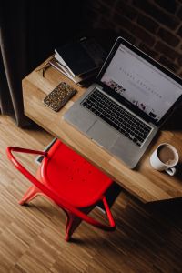 Creatives desk with laptop, camera, journals and books in front of brick wall