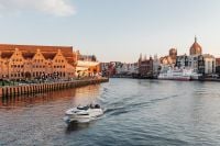 Kaboompics - Gdańsk Motława River Old Town Waterfront with Historic Granary and Passing Motorboat