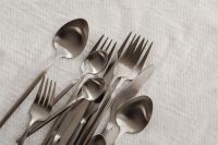 Kaboompics - Matte Steel Forks, Spoons, Knives and Teaspoons on White Fabric