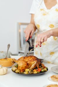 Kaboompics - Vertical Thanksgiving Scene of Woman Carving a Roast Turkey