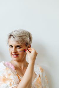 Kaboompics - Woman Applying Rainbow Face Paint to Her Cheek