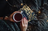 Kaboompics - Hands Holding Tea and a Hygge Book Beneath a Soft Gray Blanket