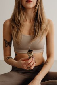 Kaboompics - Seated Woman Holding a Smoldering Sage Bundle on a Yoga Mat