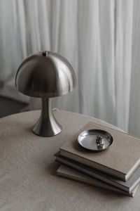 Kaboompics - Chrome Dome Lamp beside a Silver Bowl on Stacked Books, Soft Neutral Interior Styling