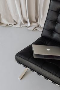 Kaboompics - Close-Up of Laptop on Black Leather Chair with Soft Curtain Background