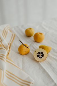 Kaboompics - Whole and Halved Japanese Quince with Dark Seeds on White Linen, Vertical Fruit Photo
