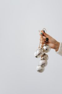 Kaboompics - Silver Baubles Hanging from One Hand Against a White Studio Backdrop