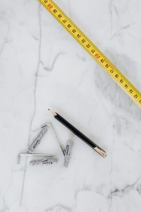 Kaboompics - Tape Measure, Carpenter Pencil and Metal Wall Anchors on White Marble, Overhead DIY Flat Lay