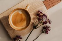Kaboompics - Close-Up of Foamy Coffee and Burgundy Astrantia on a Wooden Board