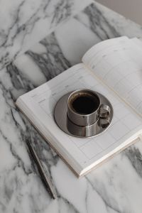 Kaboompics - Chrome Espresso Cup on Open Planner with Marble Accents, Metallic Coffee Break Still Life