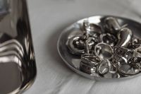 Kaboompics - Chrome Jewelry in Small Metal Bowl on White Tablecloth