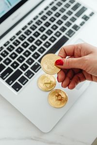 Kaboompics - Hand Holding Bitcoin Token Above Laptop