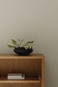 Kaboompics - Black ceramic bowl with white flowers on oak shelf