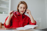 Kaboompics - Woman Holding Eyeglasses and Pencil over Open Notebook at Desk