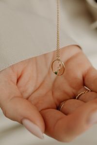 Kaboompics - Hand Holding Gold Pendant Necklace with Ring, Close-Up Jewelry Detail on Tan Silk