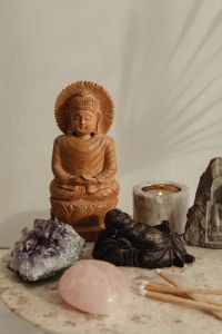 Kaboompics - Wooden Buddha With Amethyst, Rose Quartz, Candle, and Matchsticks On Marble Table