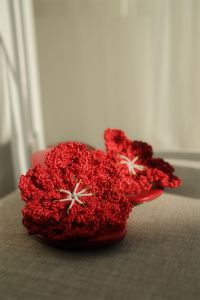 Kaboompics - Vertical Close-Up of Red Crochet Sandals on a Sunlit Upholstered Seat with Copy Space