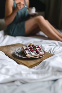 Cozy Breakfast in Bed Lifestyle with Raspberry Waffles, Coffee and White Bedding
