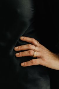 Kaboompics - Close-Up Gold Rings on Hand Against Black Fabric