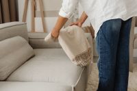 Kaboompics - Woman Folding a Throw Blanket on a Sofa