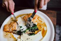Kaboompics - Hands Cutting Bourbon Glazed Salmon with Creamy Potato and Spinach at Dinner