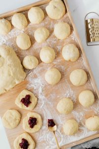 Kaboompics - Unfilled Dough Rounds and One Jam-Filled Pączek on a Board