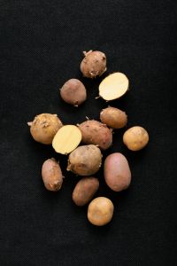 Kaboompics - Small Potatoes with Sliced Potatoes on a Black Background