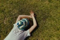 Kaboompics - Overhead Woman in Striped Hat Lying on Sunlit Grass