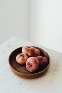 Kaboompics - Close-Up of Whole Peaches in Wooden Bowl on Light Background