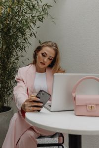 Kaboompics - Woman Using a Smartphone Beside a Laptop and Pink Handbag
