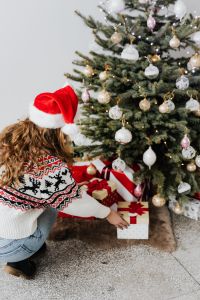 Kaboompics - Woman Placing a Wrapped Present Under a Christmas Tree