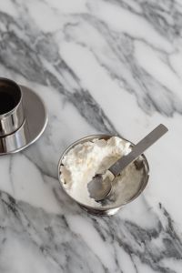 Kaboompics - White Whipped Cream Dessert and Spoon in Silver Bowl beside Espresso on Veined Marble, Coffee Break Still Life