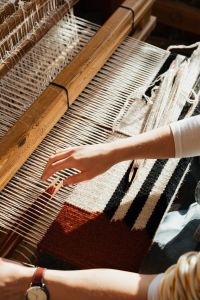 Kaboompics - Hand Weaving White Yarn into a Rust Textile