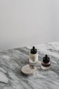Kaboompics - Skincare Serum Bottles, Silver Compact and Pearl Detail on Marble Vanity