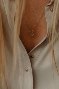 Kaboompics - Gold Pendant Necklace on Woman in Tan Silk Shirt