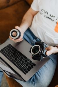 Kaboompics - Photographer Holding a Camera Lens with Laptop on His Lap