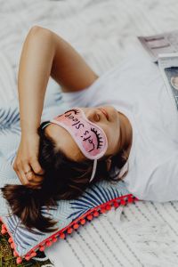 Kaboompics - Joyful girl relaxing in bedroom - top view of brunette women in pink sleeping mask