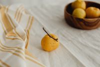 Kaboompics - Whole Japanese Quince in Foreground with Bowl of Fruit and Striped Linen, Shallow Focus