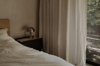 Kaboompics - Cozy Neutral Bedroom with White Bedding, Bedside Lamp and Forest View