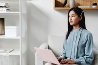 Kaboompics - Close-Up of Asian Woman Using a Pink Laptop in an Armchair