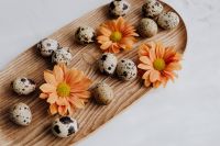 Kaboompics - Orange Gerberas and Speckled Quail Eggs Arranged on an Oval Wood Board