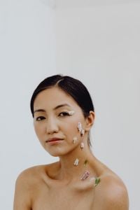 Kaboompics - Asian Beauty Portrait with Tiny Wildflowers Adorning Cheek, Neck and Shoulder