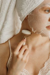 Kaboompics - Using a Facial Roller over a Sheet Mask in a Skincare Routine