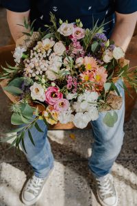 Kaboompics - Portrait of a Man Holding a Pastel Flower Bouquet on a Brown Sofa with Greenery