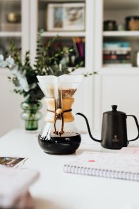 Kaboompics - Fresh Chemex Coffee in a Glass Pour-Over Carafe beside a Black Kettle and Planner in a Bright Home Office